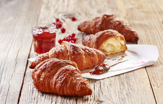 Świeże i chrupiące francuskie rogaliki croissant obok słoika dżemu