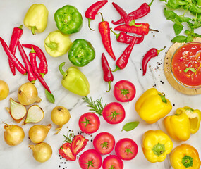 Świeże warzywa: papryka, pomidory, cebula oraz przyprawy na marmurowym blacie