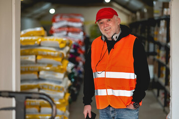 An older worker in a pet food warehouse prepares deliveries of goods for pet stores.