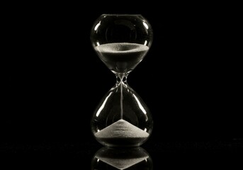 hourglass, sand, time, reflection, black background, minimalist, dramatic lighting, glass, transparent, symbolic, still life, contrast, monochrome, detail, dark mood, artistic, contemplative, time pas