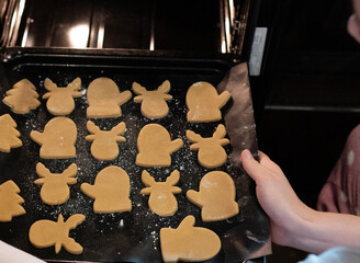 Baking cookies using metal cutters on a wooden kitchen surface during a sunny afternoon