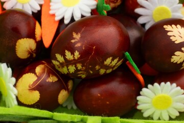 Easter bunny on a beautiful spring meadow with dandelions in front of a basket with Easter eggs