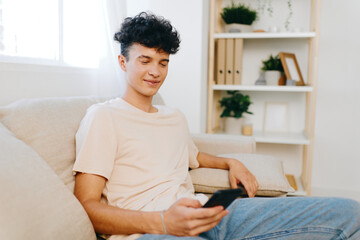 Young man relaxing at home checking phone, casual attire, cozy interior with plants