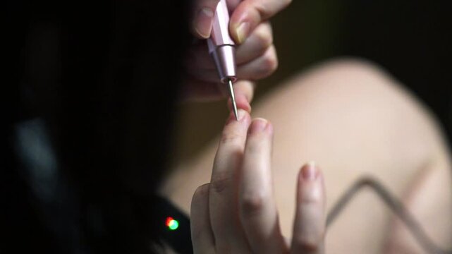 woman hands using a nail buffer on her nails after cuticle removal, showcasing a professional manicure process in slow motion