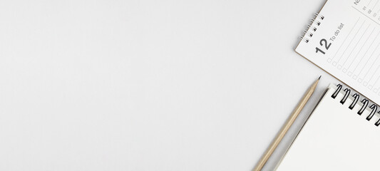 Top view of white desk with notebook, pencil, and 12 month to do list. Concept of planning, reminders, and goal setting for this year. with copy space