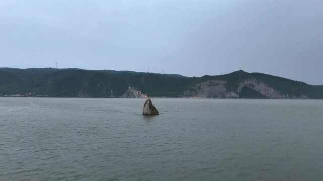Sailing boat by coastal houses and green mountains in Cazanele Dunarii , Moldova Veche, Romania