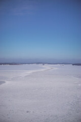 Beautiful winter lake landscape. View on the high bridge. Frozen lake, islands, forest and blue sky. Winter season in Finland.