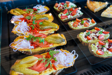 Assorted open-faced sandwiches with fresh toppings in a display case.
