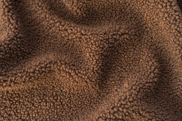 Textured close-up of thick, fluffy brown teddy fleece fabric. © Valeriia
