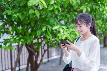 笑顔でスマホを見ながら歩く若い女性