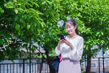 笑顔でスマホを見ながら歩く若い女性