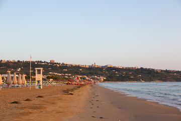 A scenic coastal view featuring a lifeguard tower on a deserted beach with a calm ocean 