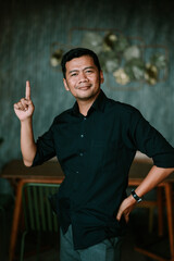 Confident man pointing upward displaying positive affirmation indoors