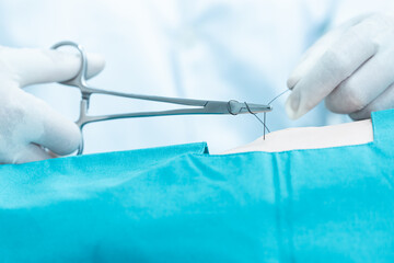 Doctor hand wear sterile gloves and surgery scissor stitching up wound after surgery.Plastic...