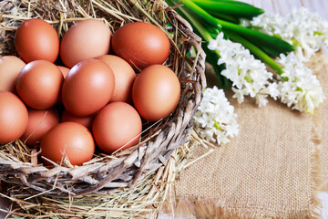 A big wicker basket with hen eggs on hay.