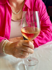 Person holding a large glass of rose wine in a restaurant.