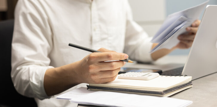 close up young man hand press on calculator and open over group of invoice letter mail from bank after pass due date of payment for money and debt management concept	