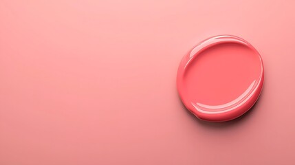 A smooth, circular blob of coral-colored paint rests on a soft pink background, creating a harmonious and modern aesthetic.