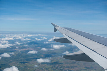 Sky and cloud seen through the window of airplane, with the plane wing