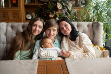 woman with three children on the sofa at the table. happy family, two brothers and one sister.