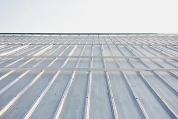 a close-up view of a metal roof, likely made of corrugated steel or aluminum panels. The perspective is from the bottom looking upwards, emphasizing the linear patterns and structure of the roof.