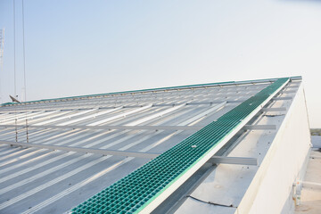 a green fiberglass grating panel installed on a metal framework. The grating panel has a grid-like...