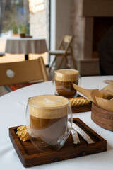 Latte in a transparent glass on a table in a cafe.
