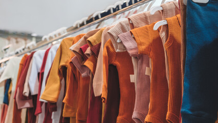 A rack of clothes with a variety of colors and styles. The clothes are hanging on a rack, and the...