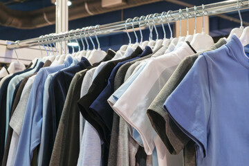 A rack of clothes with a blue shirt hanging from the top. The clothes are hanging on a rack and are of different colors