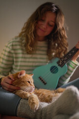 Cozy home scene featuring a young woman playing a turquoise ukulele while gently petting her...