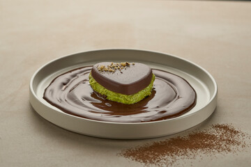Trending Dubai Chocolate with vibrant green pistachio and kataifi dipped in melted chocolate and plated on modern beige plate. Modern luxury set up, trendy dessert