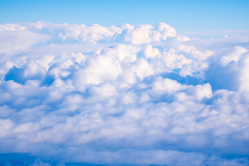 Fototapeta premium Fluffy clouds emerging under a bright blue sky during a sunny afternoon above mountain ranges