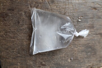 Transparent plastic bag filled with water resting on rustic wooden surface