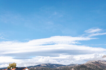 Lenticular clouds against blue sky over  montains.