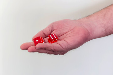 Man's hand holding 2 red dices isolated on white background.