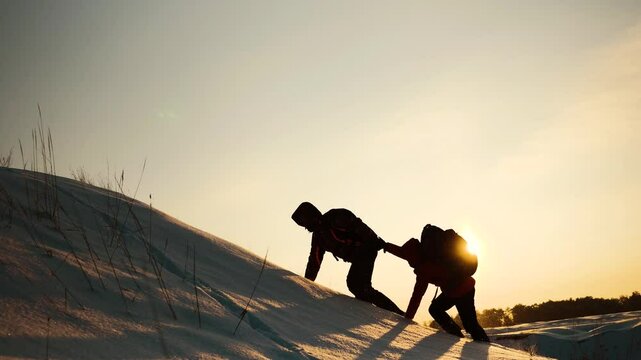 teamwork. concept of group travel to mountains of tourists. silhouette climbers man and woman against the sky with backpacks. silhouette happy people sunset. helping hand. joy happiness help friend