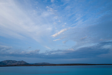 Isola Piana seen from La Pelosa beach at sunset in Stintino in Europe, Italy, Sardinia, Stintino, in summer, on a sunny day.