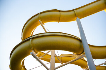 Water Slides Park Summer Fun: Yellow water slides curve against a bright blue sky.
