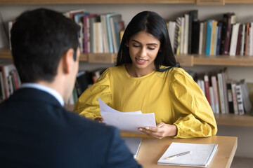 Paperwork in academic study. Focused female teacher mentor read essay check test form on exam in...