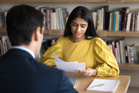 Paperwork in academic study. Focused female teacher mentor read essay check test form on exam in presence of student. Young girl scholar give feedback on male groupmate project draft on peer review.