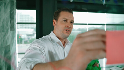 Skilled businessman presents marketing idea to project manager by using colorful sticky notes at...