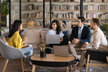 Supportive learning atmosphere. Confident young woman teacher coach trainer lead casual meeting workshop seminar teambuilding activity at comfy coworking space in diverse multicultural students group