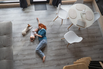 Top view of caucasian woman lying on floor with newborn son and jack russell terrier dog. 
