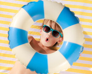 Top view portrait of happy child lying on beach towel on summer vacation