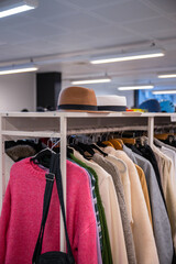 Obraz premium Clothing rack filled with sweaters, jackets, and hats in a thrift store. 