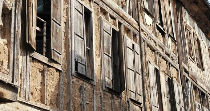 This photo shows the weathered facade of a wooden house in detail. The natural texture of the wood, the window details and the overall rustic feel of the structure are striking.