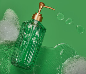Hand and face soap in a glass dispenser with some bubbles and water around it.
