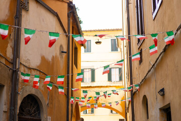 Typical street with houses in Italy. Facade of a yellow building with Italian flags. Italian flag...