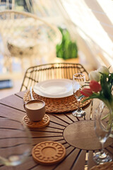 cup of coffee on a wooden table near flowers