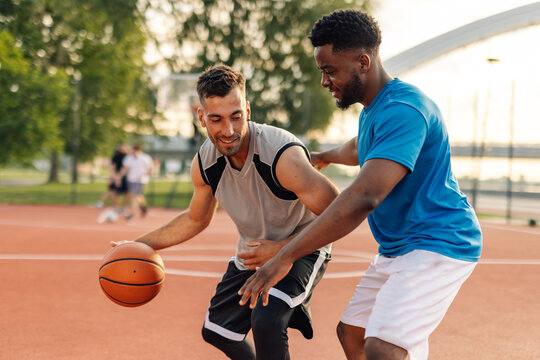Two basketball players playing one on one on outdoor court - Powered by Adobe